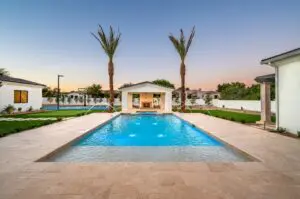 A pristine pool in a white house with two palm trees