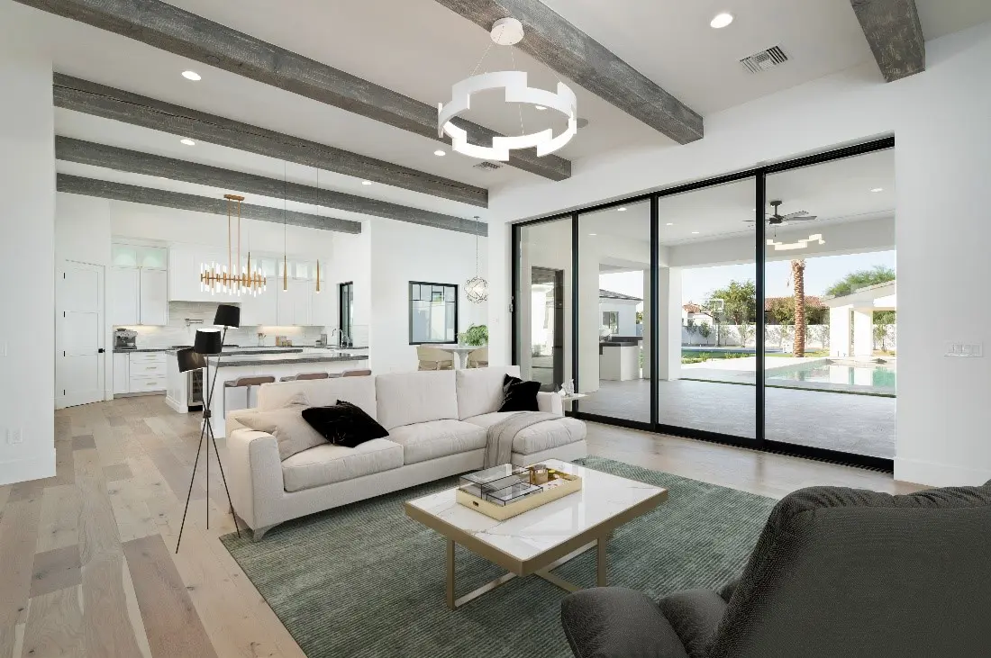 A living room with white walls, glass windows, and white and gray couches