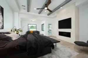 A bedroom with white walls, a black bed, and a TV